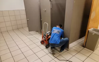Plumber repairing a commercial toilet in Nogales bathroom