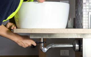 Plumber repairing a bathroom sink in Nogales home